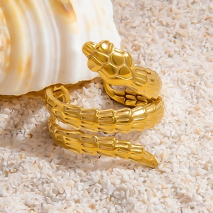 Minimalist gold-plated stainless steel snake ring displayed on white stones with shell decor