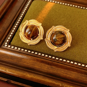 Detailed close-up of vintage golden tiger eye earrings on a green velvet display stand