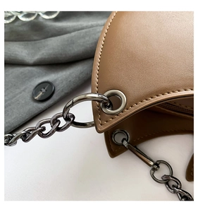 Detail of warm brown leather bag with gunmetal chain and premium stitching texture