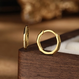 Macro shot of S925 sterling silver golden geometric hoop earrings on a luxury jewelry box