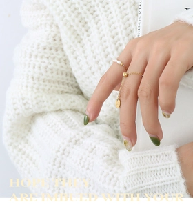 Détail d'une bague chaîne ajustable en or 18 carats avec perles et breloque K18