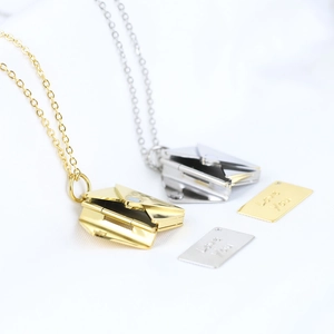 Detailed view of gold and silver envelope necklaces with Love You engraved inserts