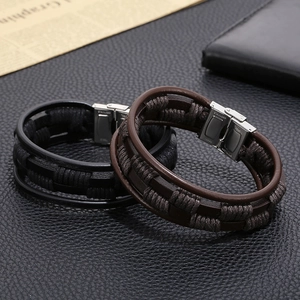 Detail of multi-layer woven leather bracelets in black and brown with steel clasp