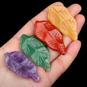 Handheld view of four leaf-shaped carved natural agate crystals in purple, green, red and yellow