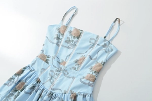 Dettaglio vestito azzurro con motivi a rose rosa e cuciture in pizzo bianco traforato
