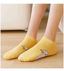 Close-up of yellow low-cut socks with cute cartoon duck pattern on wooden floor