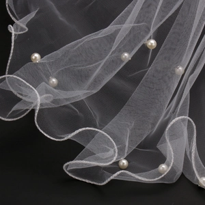 Elegant white wedding veil with handmade pearls on soft mesh fabric against black background