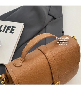 Detail of a brown lychee pattern leather handbag with sturdy handle and gold hardware