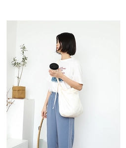 Lifestyle shot of a white minimalist canvas crossbody bag styled with casual outfit