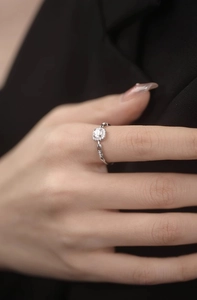 Close-up of sparkling square diamond chain ring worn by a model on a dark background