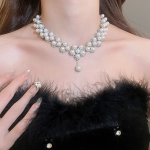 Detail of pearl necklace with diamond flower motif and teardrop pearl pendant on model