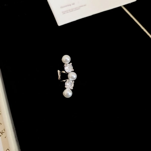 Détail du clip d'oreille en perles et zircons avec monture argentée sur fond noir
