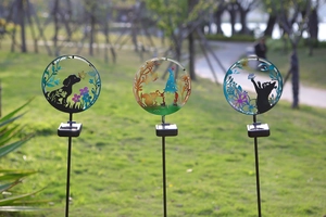 Three solar garden stakes featuring dog, elf, and cat silhouettes on a green lawn