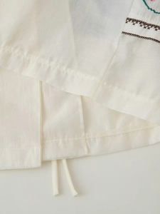 Gilet brodé à cordon en blanc crème avec finition en tissu brillant et floral