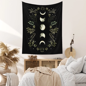 Detail of bohemian black moon phase tapestry with watercolor floral patterns on a bedroom wall