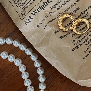Close-up of a 925 silver gold-plated twisted ring and elegant white pearl necklace