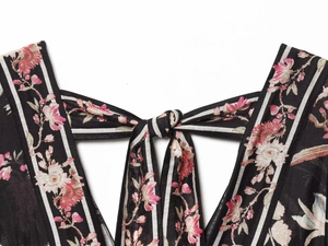 Detailed view of the bow-tie ribbon back and floral bird print on black fabric