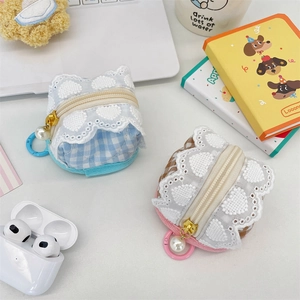 Close-up of cute plaid fabric earphone cases with lace trim and pearl pendants on desk