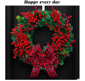 Close-up of a Christmas wreath with red berries, pine needles and a buffalo plaid bow