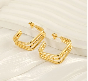 Close-up of layered gold square earrings with polished and twisted metal textures
