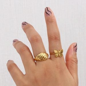 Detail of gold-plated croissant ring and butterfly ring on model's hand with nail art