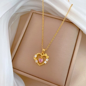 Detail of gold heart pendant with pink zircon and butterfly on silk background