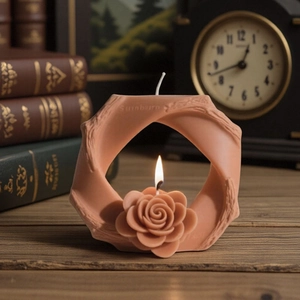 Candela profumata a forma di rosa in un supporto ad anello rosa su scrivania in legno
