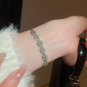 Macro view of flower-shaped zircon links on silver pearl bracelet with adjustable chain