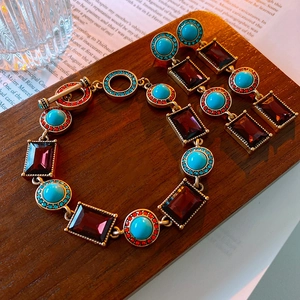 Detail of vintage jewelry set with turquoise stones and OT buckle on wooden tray