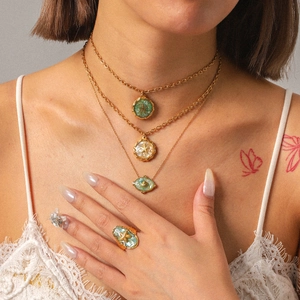 Close-up of gold starfish necklace and ring set with green resin on model neck