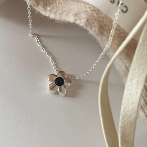 Minimalist S925 sterling silver floral necklace with black gemstone on elegant beige fabric