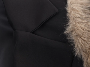 Detail of black woven coat featuring contrasting beige faux fur trim texture