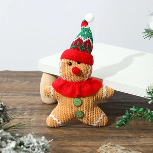 Knitted gingerbread man doll with red scarf and Christmas hat on a wooden floor