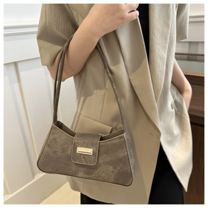 Detail of a brown suede baguette shoulder bag with metal buckle on a beige blazer