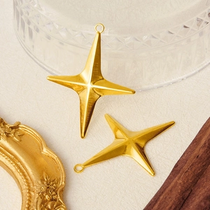 Pair of 18k gold plated stainless steel star charms on a decorative background