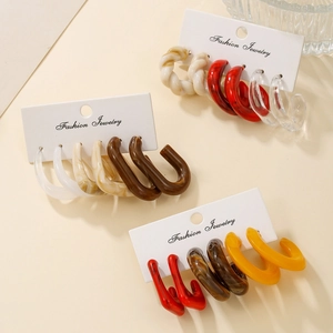 Close-up of assorted resin C-shape hoop earrings on cards in marble, red and amber patterns