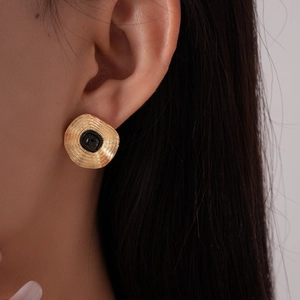 Gros plan d'une boucle d'oreille ronde dorée vintage avec pierre noire sur l'oreille
