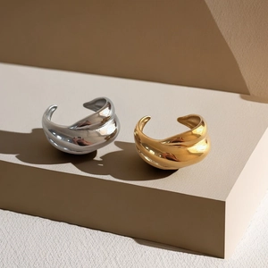 Twisted sculpture rings in 18k gold and silver plating on minimalist beige background