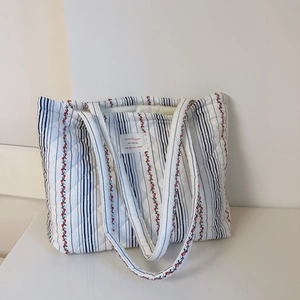 Détail du motif de matelassage en losanges et de l'imprimé floral sur le sac en coton