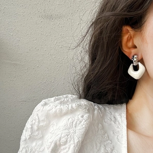 Minimalist white geometric drop earrings with silver textured hoops on female model