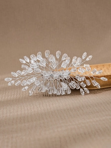 Close-up of handmade bridal hair comb with clear crystals and silver beads on beige fabric
