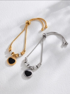 Détail de bracelets cœur ajustables en or et argent avec cristaux sur tissu blanc