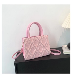 Detail of pink crossbody bag featuring 3D diamond fringe pattern and round handles
