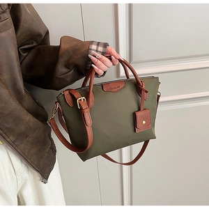Close-up of olive green nylon tote bag with brown leather handles and adjustable strap