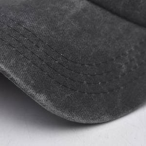 Macro view of baseball cap brim showing parallel stitching and washed cotton texture