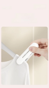 Close-up of a hand using a white plastic clothespin to secure laundry on a gray hanger