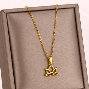 Detail of a gold lotus pendant necklace with a green gemstone on a premium jewelry box