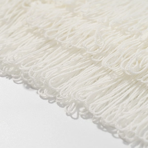 Makro-Detail weißer Fransenbesatz mit feiner Stricktextur und weichen Garnfäden