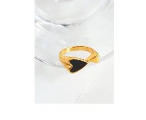 Close-up of a minimalist 18K gold-plated open ring with black enamel and gold heart details