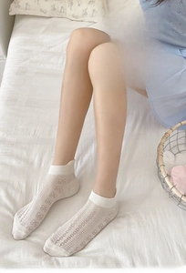 Close-up of white mesh socks featuring bow patterns and breathable sheer fabric texture